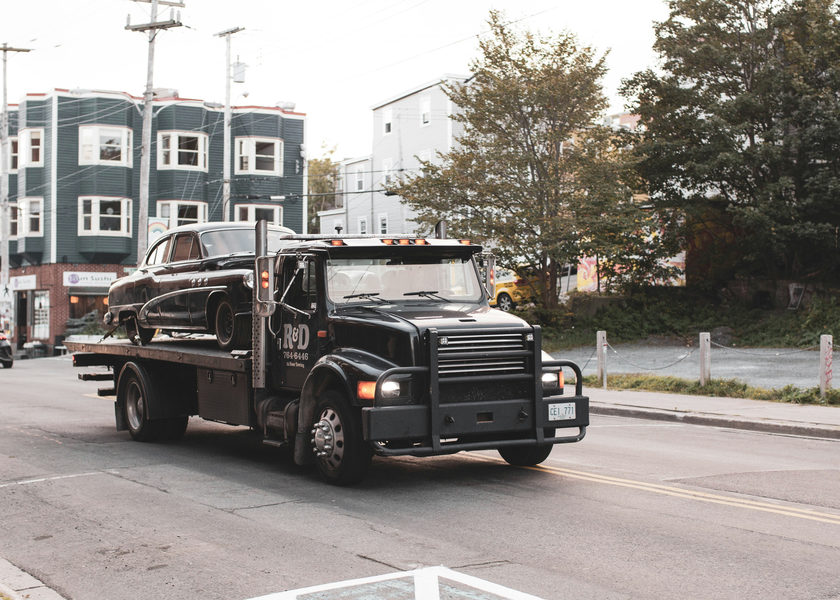 A black tow truck towing a vehicle