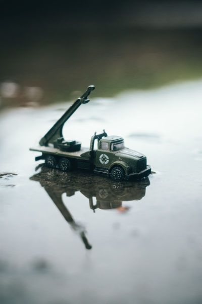 A green toy towing truck in a puddle of water
